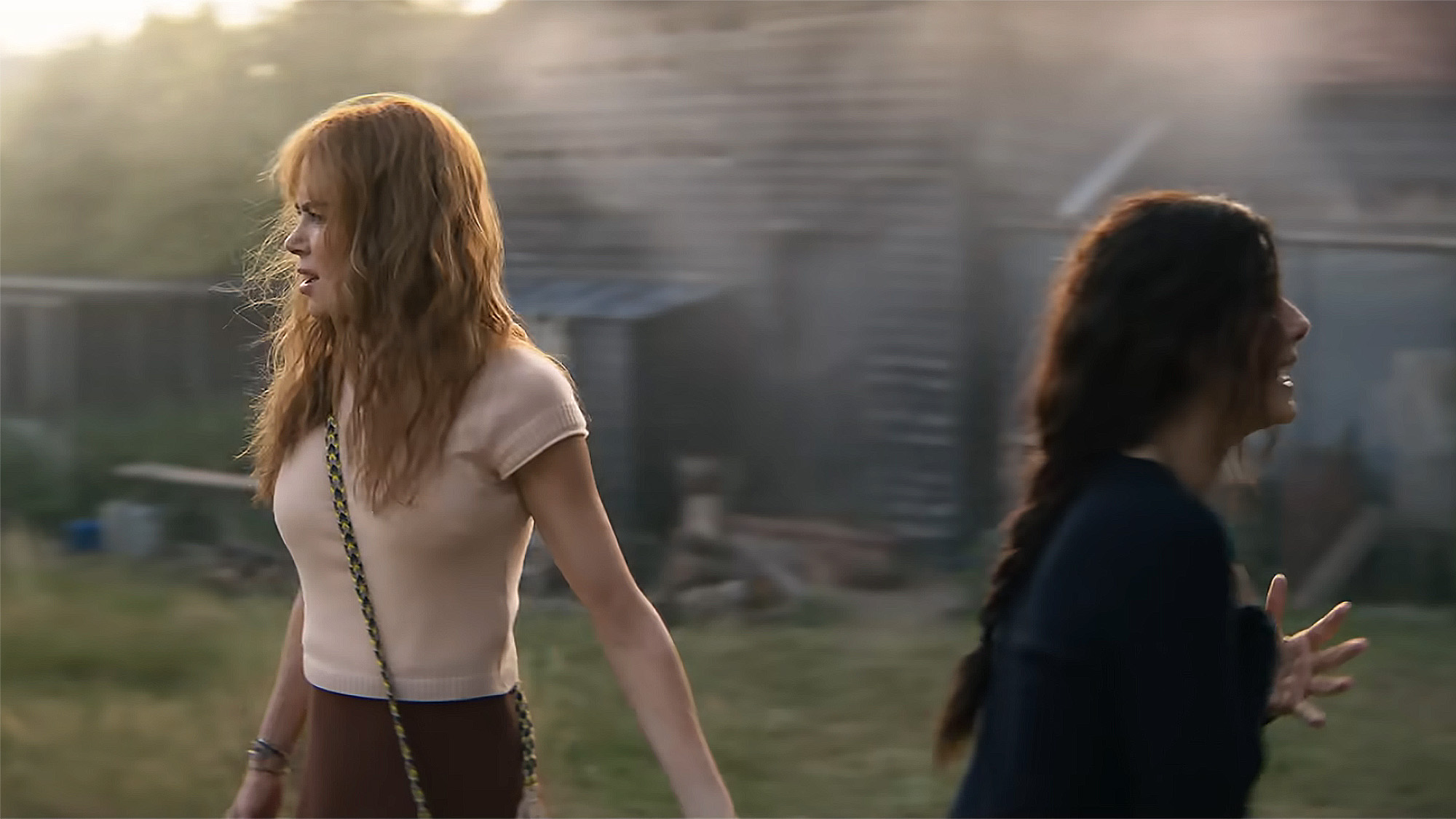 Nicole Kidman and Sandra Bullock stand back-to-back out in English nature in Practical Magic 2 scene.
