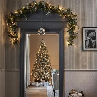 Christmas tree in a hallway with fairy lights and present underneath