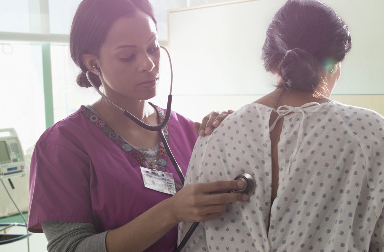 Nurse listening to heartbeat of patient in hospital room