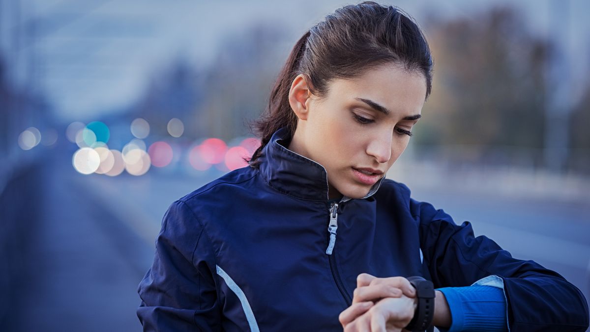 Woman wearing running jacket looks at her running watch