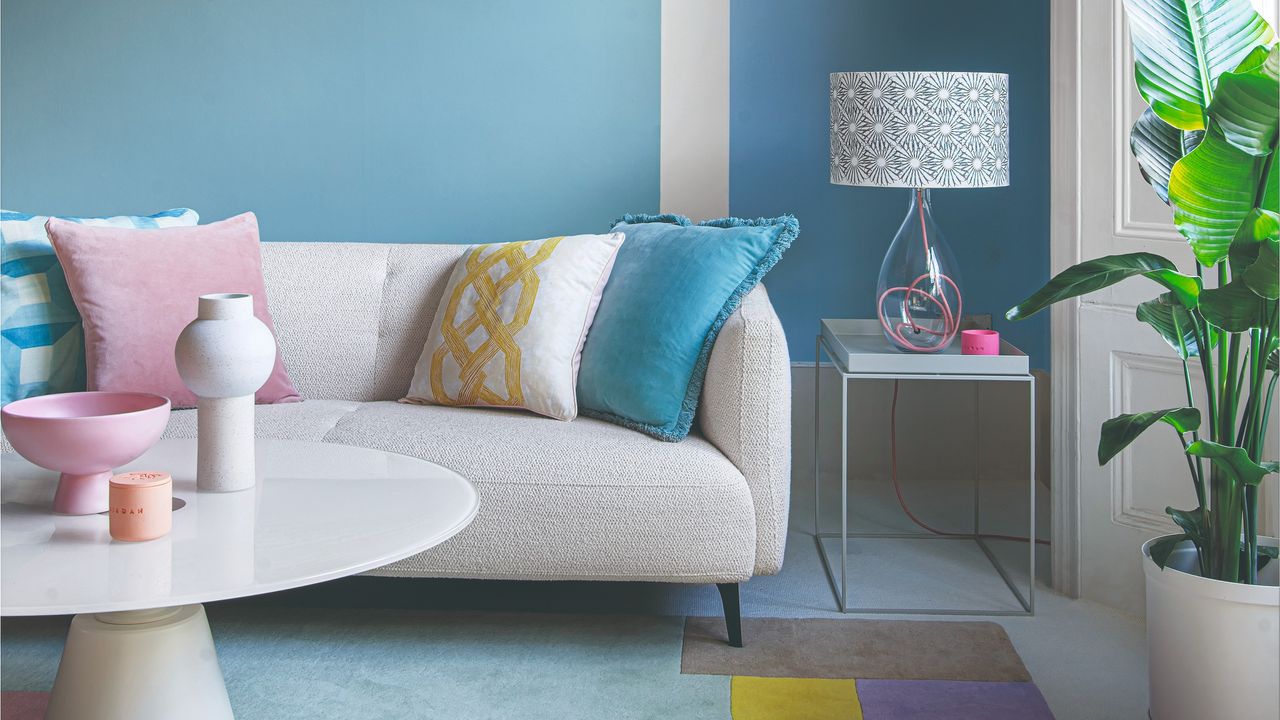 A blue-painted living room with a white boucle sofa and multi-coloured cushions