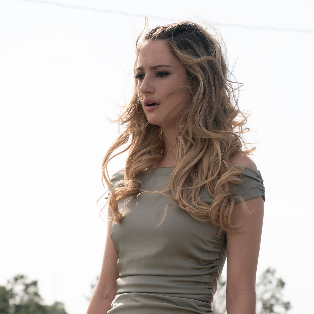 grace van patten as lucy in a green dress looking shocked outside of a gas station in tell me lies season 3 finale
