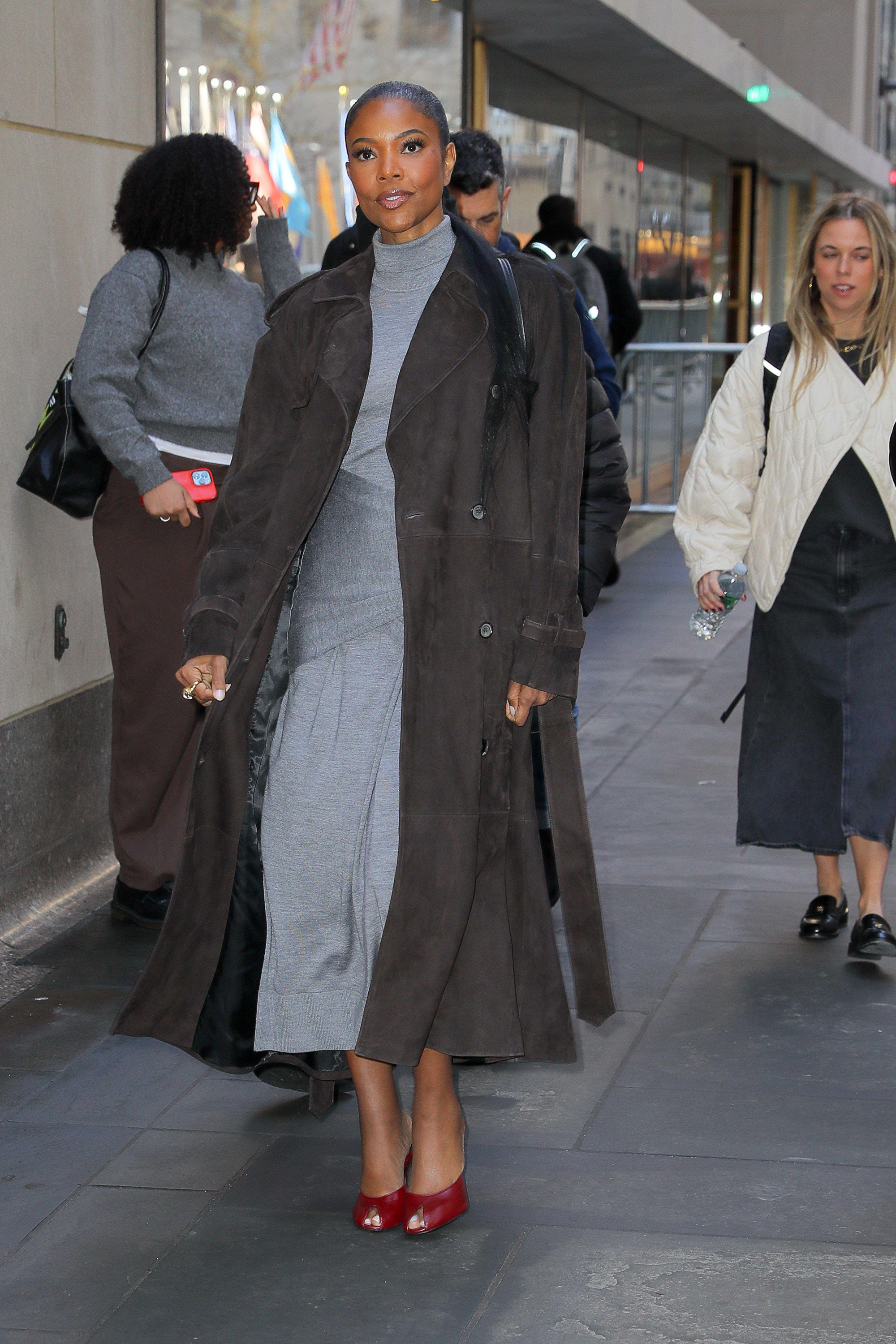 gabrielle union wearing a trench coat, a dress, and red heels