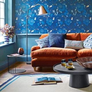 a living room with blue wallpaper and an orange sofa