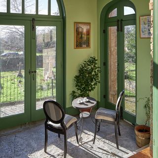 room with green wall and glass door and round table with chairs