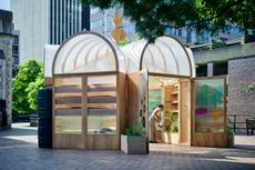 The Veggery, a greenhouse pavilion installed outside in a London plaza, made of wood and featuring a variety of plant pots on shelves