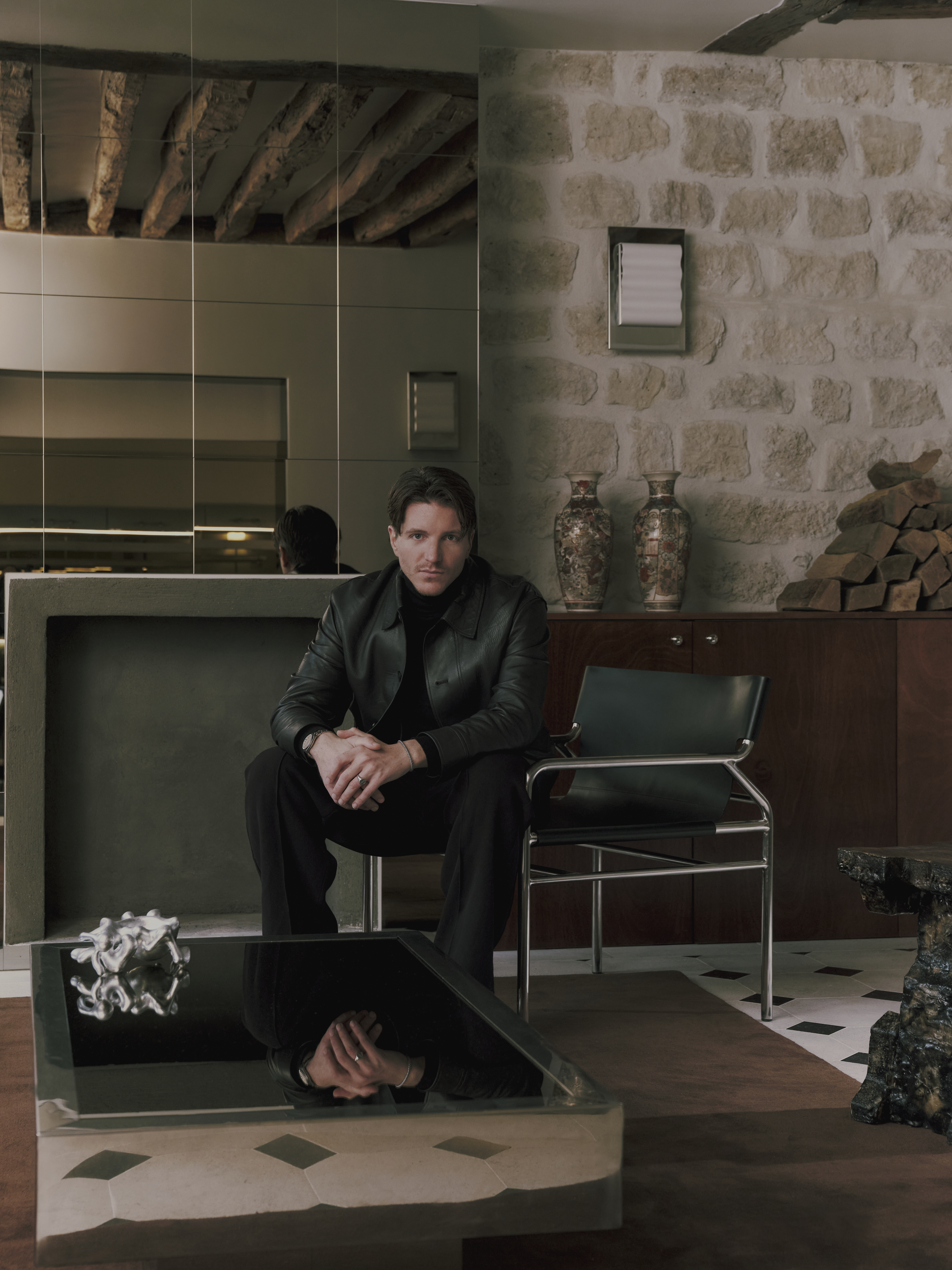A sleekly designed apartment with tiled white and black checkered floors, chrome surfaces, brick walls, and occasional pops of red, ming green, and butter across linearly cut furniture.