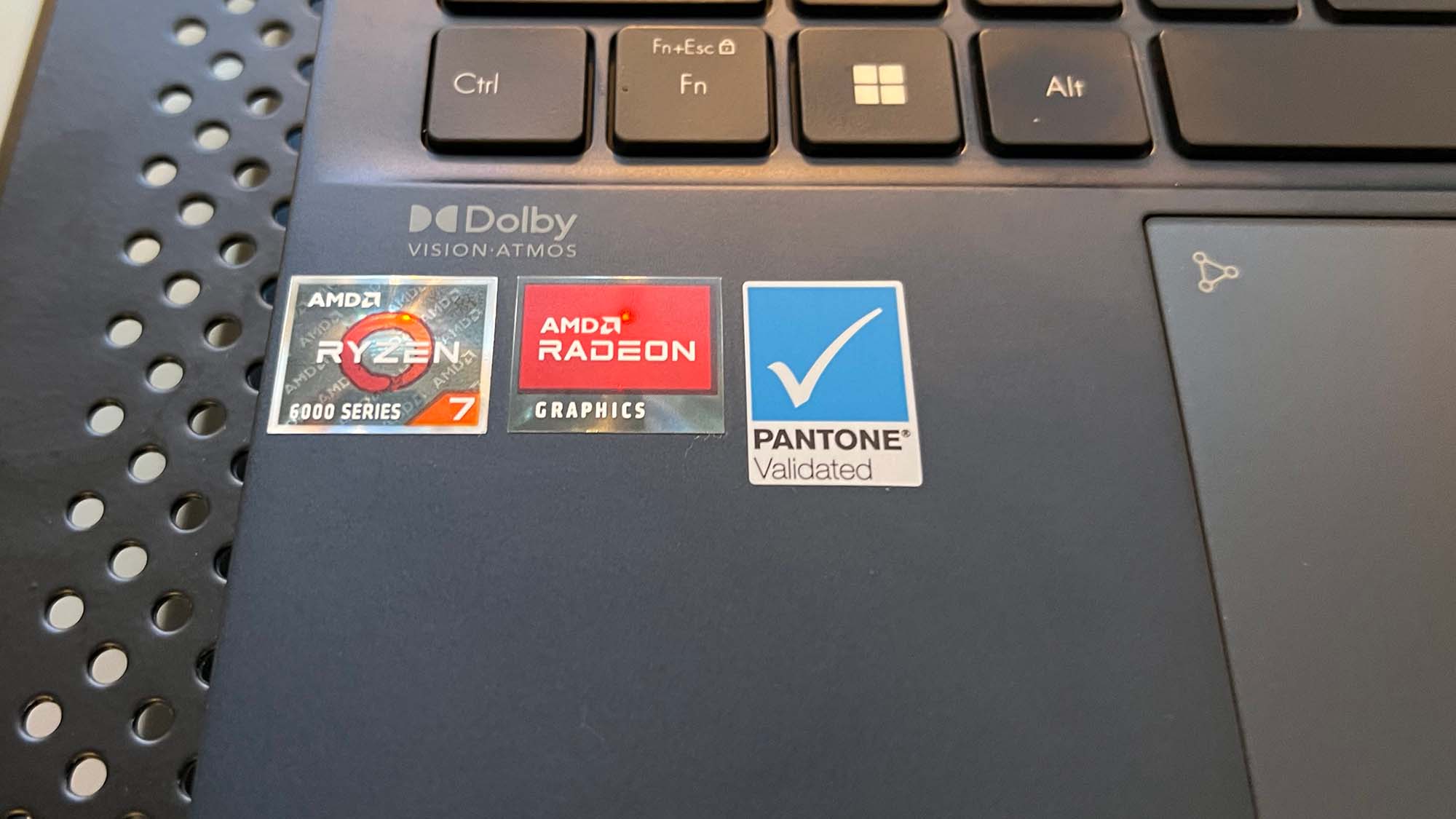 Eine Nahaufnahme der AMD-, Radeon- und Pantone-zertifizierten Aufkleber auf dem Asus Zenbook S 13 OLED