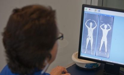 A Transportation Security Administration employee looks at an image from a full-body scanner.