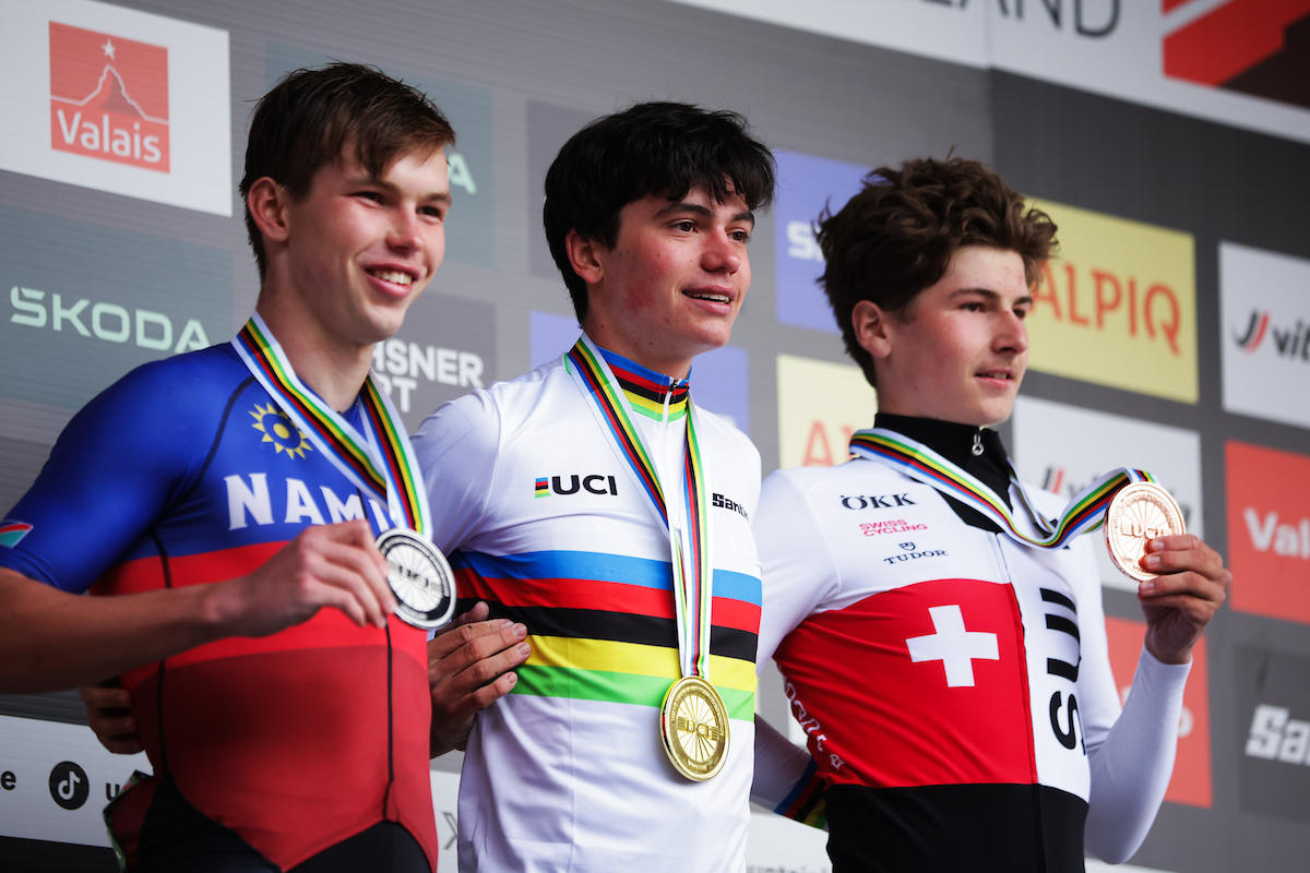 Picture by Ed Sykes/SWpix.com - 12/09/2025 - Cycling - 2025 UCI Mountain Bike World Championships - Cross-country Olympic - Crans Montana, Valais, Switzerland - Men Junior Podium - Lucas Teste (France) receiving the Gold Medal to become World Champion with Roger Suren (Namibia) receiving the Silver Medal and Lewin Iten (Switzerland) receiving the Bronze Medal