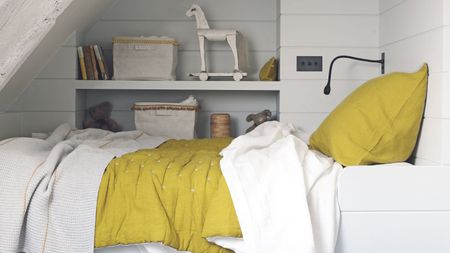 A kids bedroom with open shelves and a messy bed