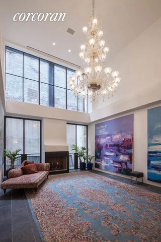 A large entryway with big windows, Persian style rug, chaise longue and a fireplace
