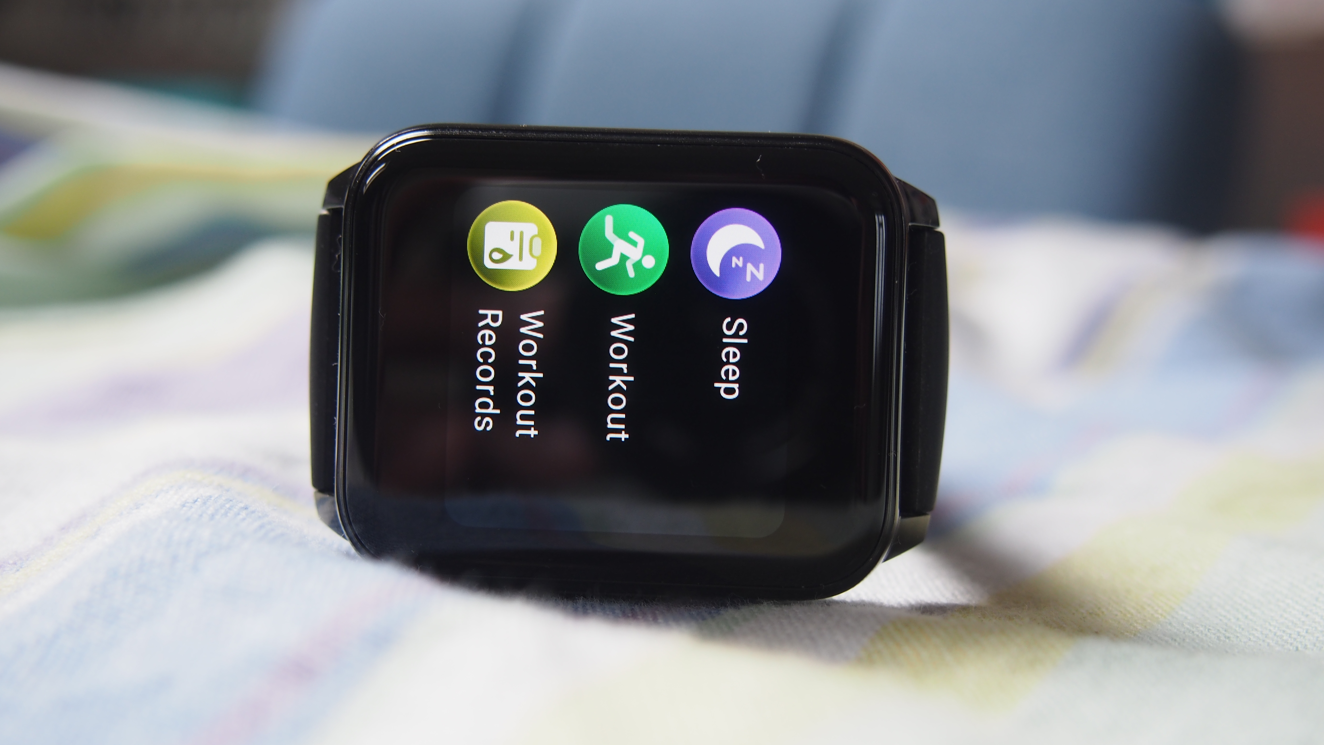 Realme Watch 2 on its side, with sleep, workout, and workout records icons on its screen