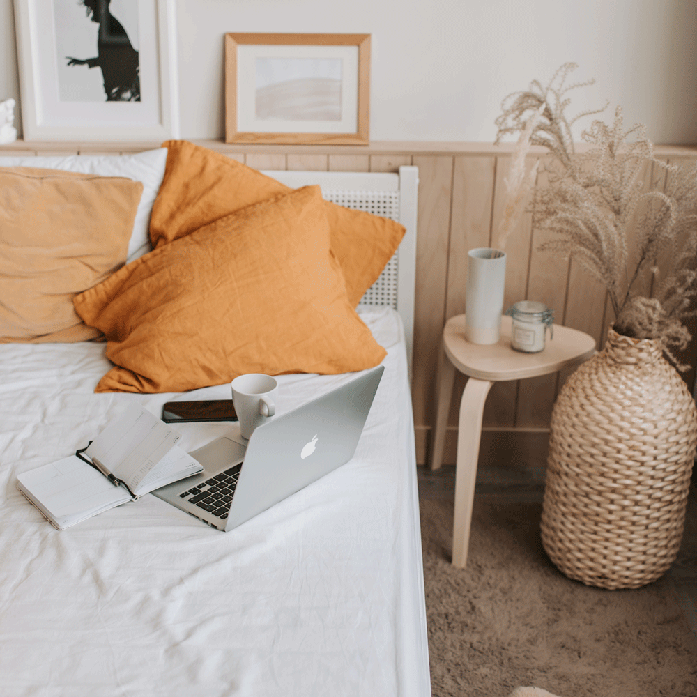 bedroom with orange pillow and laptop