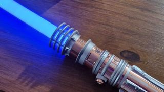 Leia Organa Force FX Elite Lightsaber ignited on a wooden table