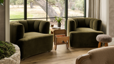 two green velvet armchairs next to the window in a bedroom with timber side table, boucle ottoman, and light oak flooring