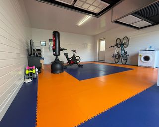 A garage home gym with blue and orange flooring