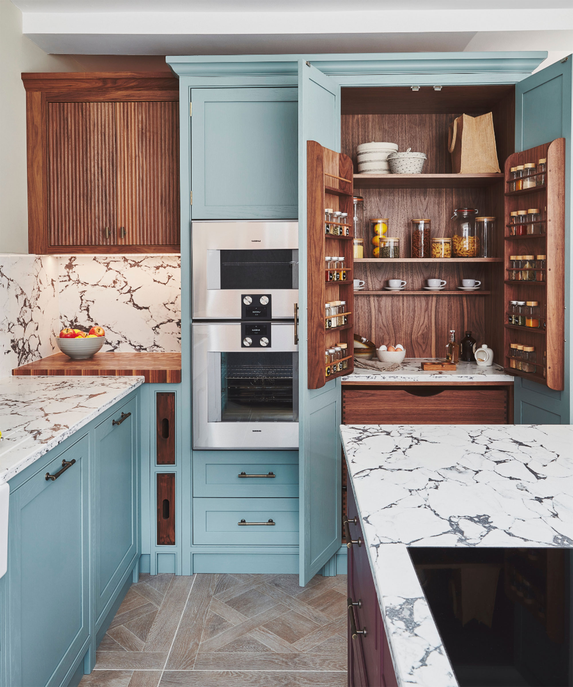 pale blue Shaker kitchen with pantry cupboard featuring a warm wood interior