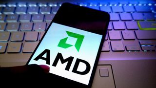 The AMD logo on a smartphone with a laptop in the background