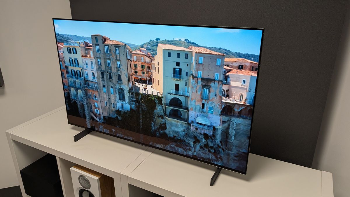 The LG C5 42-inch OLED TV on a TV cabinet seen at an angle. On screen are apartment buildings in a traditional Italian town.