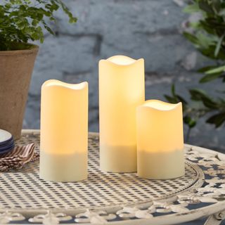 Set of three flameless candles on a metal garden table