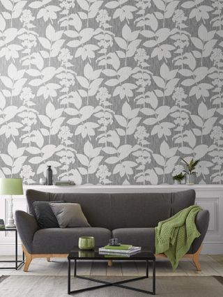 Aspen Grey wallpaper from Graham & Brown in a modern grey living room, with a grey sofa and green furnishings including a lamp and a throw