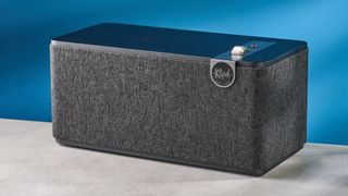 Klipsch The One Plus Bluetooth speaker in matte black photographed in front of a blue background.