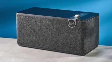 Klipsch The One Plus Bluetooth speaker in matte black photographed in front of a blue background.