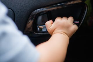 child grabbing car handle inside car