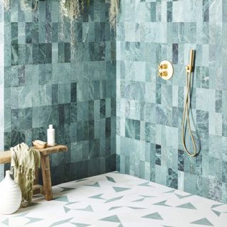 A shower room with blue encaustic wall tiles and hexagonal floor tiles