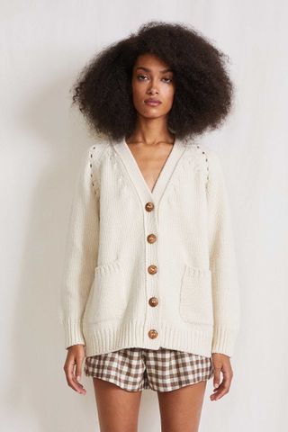 A model wearing a white cardigan sweater by Apiece Apart