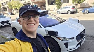 Hamish stood next to a Waymo car