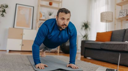 A man performing a push-up at home as part of an arm workout