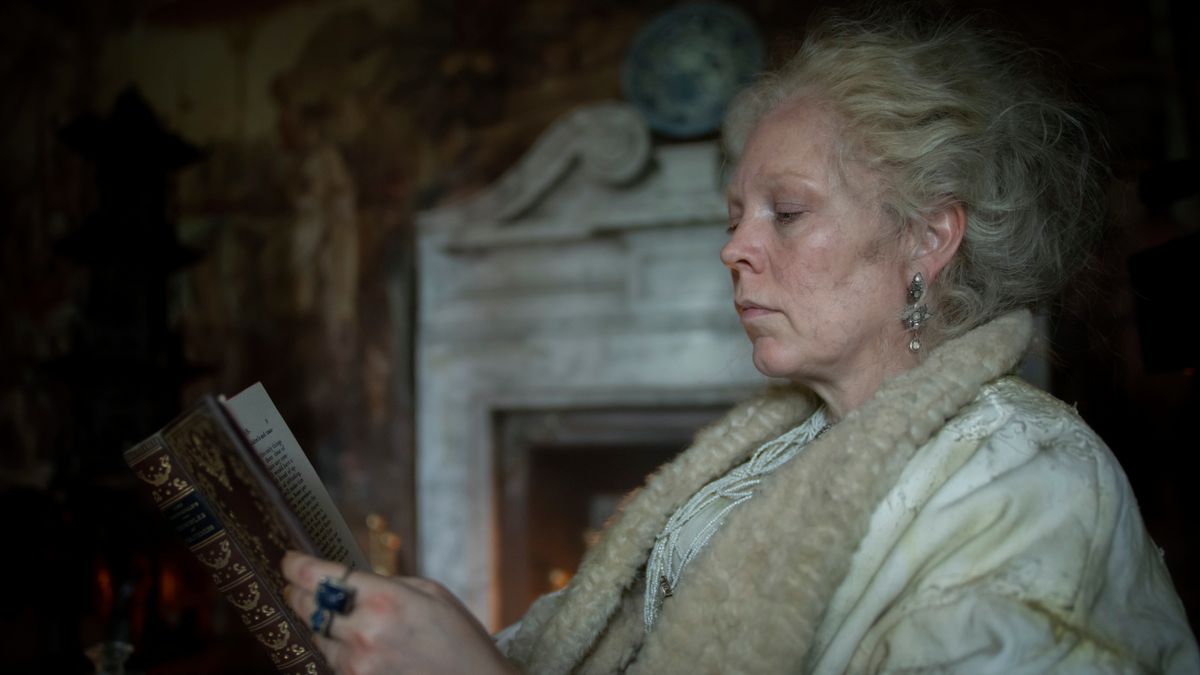 Miss Havisham (Olivia Colman) reading a book.