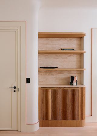 A wooden cabinet with shelves next to a white door.