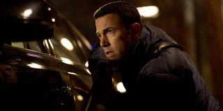 Ben Affleck takes cover behind a car in The Accountant.