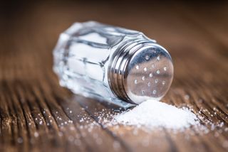 A tipped-over salt shaker with spilled salt.