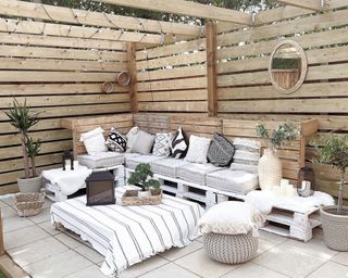 An outdoor living area with pallet coffee table covered with white throw decor