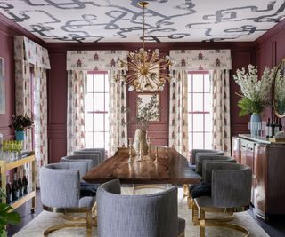 Burgundy walls, white ceiling with black pattern, grey dining chairs