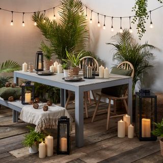 balcony/paved garden area with table and chairs, plants, festoon lights, candles