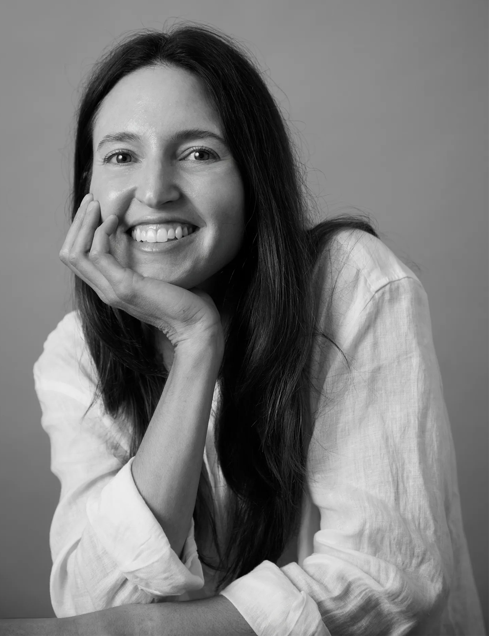a black and white photo of a woman smiling in a white shirt