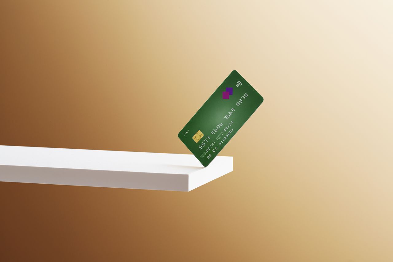 A debit card balanced on the edge of a shelf