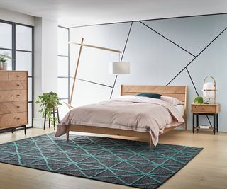 bedroom with linear design on the wall, wooden Ercol furniture and a green rug