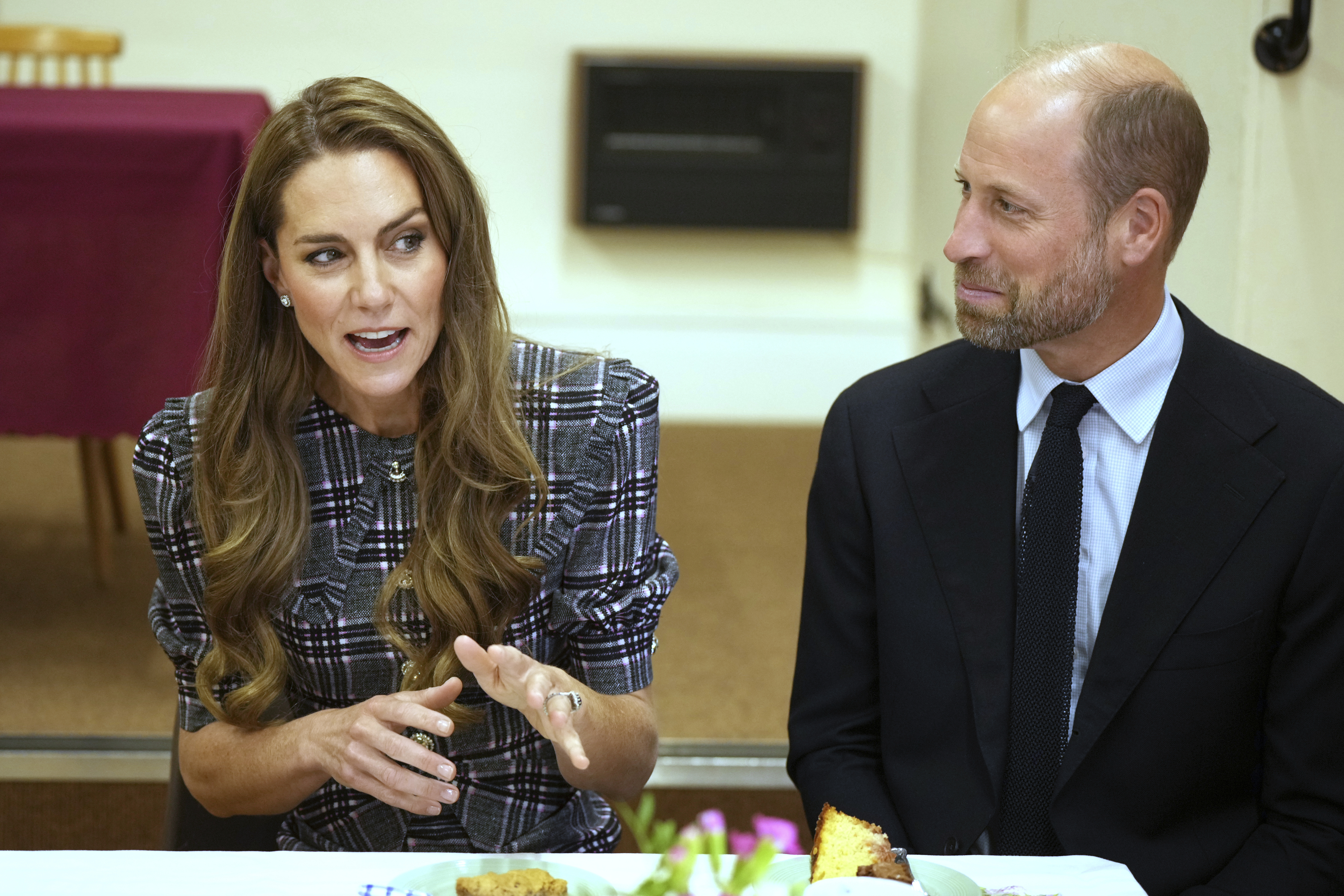 Prince William and Princess Kate sitting at a table talking and smiling