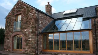A timber frame extension built next to a stone dwelling