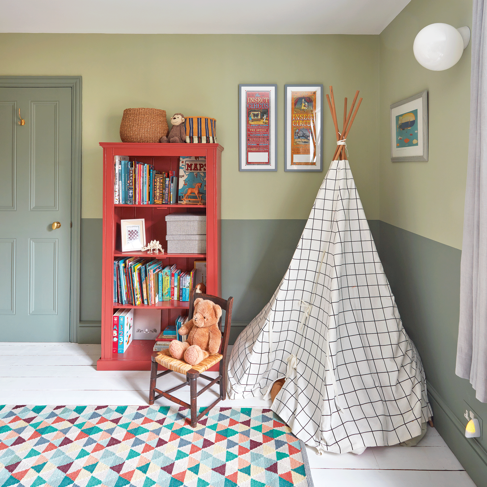 a child's bedroom with two tone green painted walls, a teepee and a red bookcase