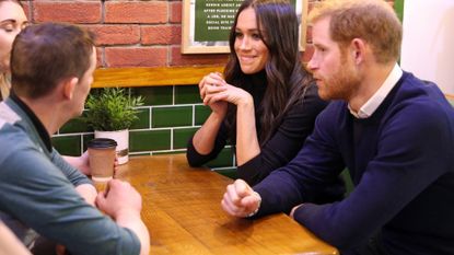 Britain's Prince Harry (R) and his fiancée US actress Meghan Markle speak to members of staff on a visit to Social Bite, a business and cafe, during a visit to Scotland on February 13, 2018. Social Bite runs social enterprise cafés throughout Scotland and use this platform to distribute 100,000 items of food and hot drinks to homeless people each year, as well as employing staff who have experienced homelessness themselves. 