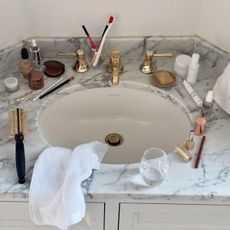 An array of beauty products on a marble sink side