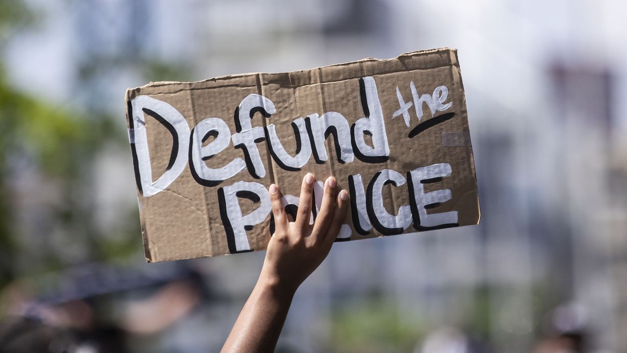 manhattan, ny june 19 a protester holds up a homemade sign that says, &quot;defund the police&quot; with the manhattan bridge behind them as they perform a peaceful protest walk across the brooklyn bridge this was part of the unite ny 2020, bringing all of new york together rally and march for black lives matter as protests that happened around the country to celebrate juneteenth day which marks the end of slavery in the united states protesters continue taking to the streets across america and around the world after the killing of george floyd at the hands of a white police officer derek chauvin that was kneeling on his neck during for eight minutes, was caught on video and went viral during his arrest as floyd pleaded, &quot;i can&#039;t breathe&quot; the protest are attempting to give a voice to the need for human rights for african american&#039;s and to stop police brutality against people of color they are also protesting deep seated racism in america many people were wearing masks and observing social distancing due to the coronavirus pandemic photographed in the manhattan borough of new york on june 19, 2020, usa photo by ira l blackcorbis via getty images