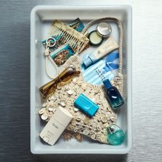 A photo of an airport tray filled with beauty products and accessories